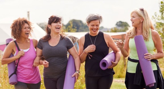 four women walking outdoors with yoga mats